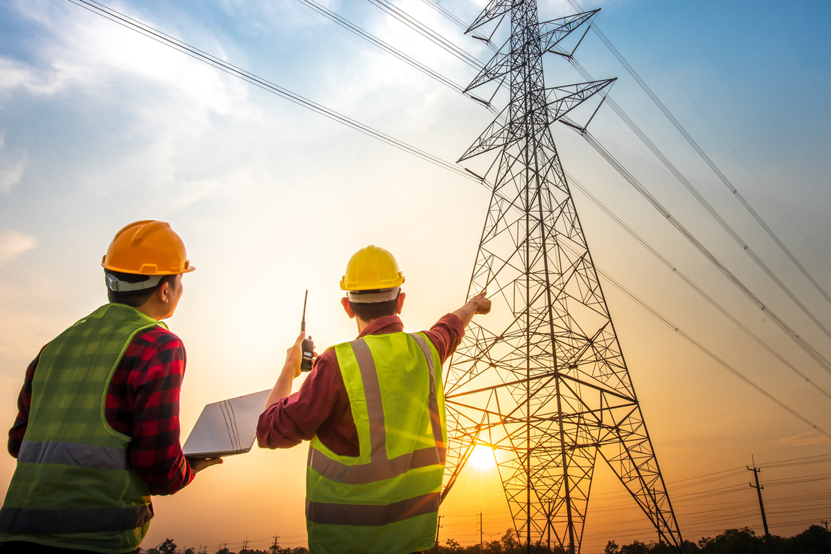 Electrical workers looking at high voltage power station